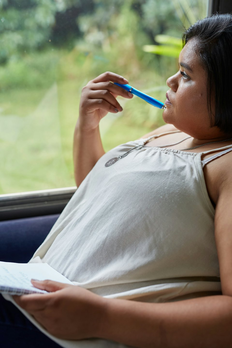 Eine Frau mit einem Stift an den Lippen und einem Notizbuch.