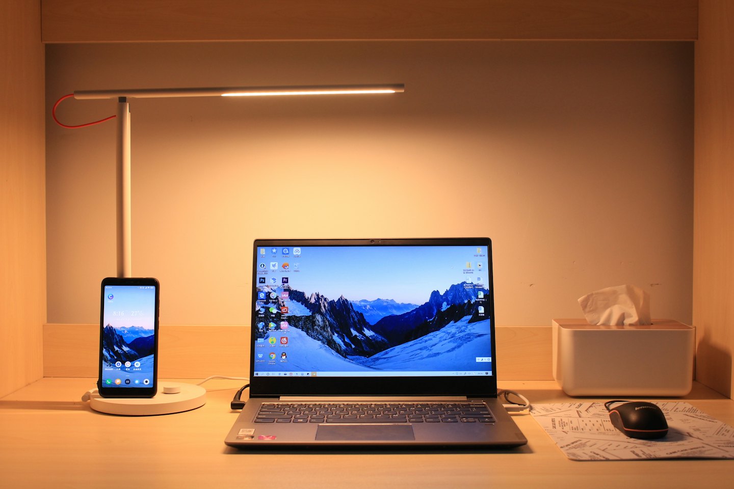 Laptop und Smartphone laden auf einem Holztisch.